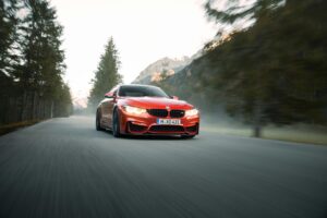 High-speed red sports car driving through scenic mountain road with blurred background